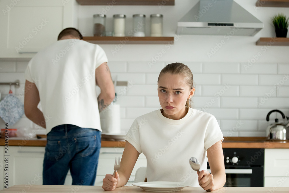 Hungry wife sit at table dissatisfied with man cooking dinner, funny ...