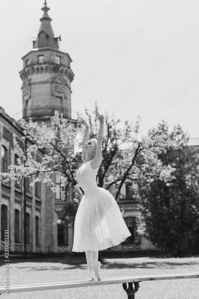 Obraz premium Ballerina dancing on the street.Young beautiful ballerina in dress and pointe shoes dancing outdoors. Ballerina posing in the center of Europe