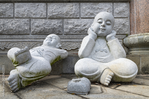 Two sculptures representing bouddha sitting and laying on the floor against the wall of the "Kok Lok Si", in Chinese, temple located in Penang, Malaysia