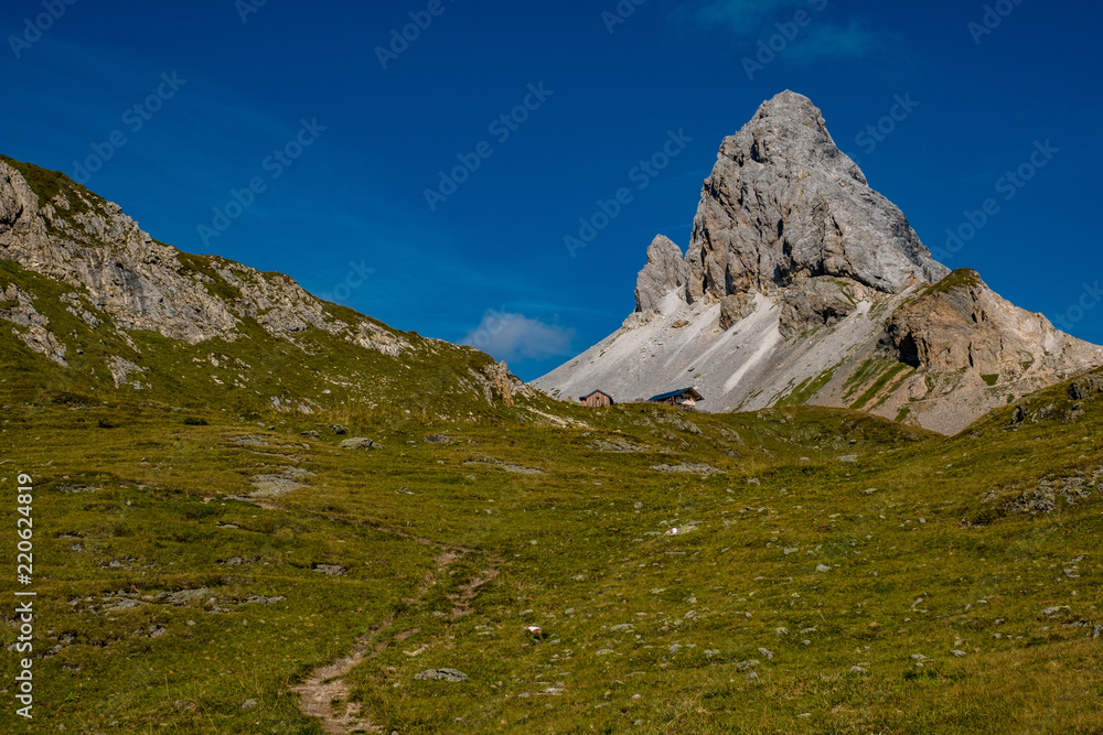Markanter Gipfel überragt eine grüne Almenlandschaft in den Bergen Österreichs