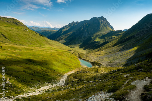 Türkisblauer Bergsee in einem idyllischen Gebirgstal in österreich mit saftig grünen Almen
