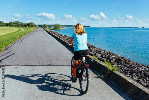 Canvas Print Blonde woman is cycling along the bike path around the Lac du Der Chantecoq in F