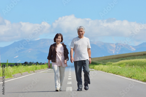 一本道を歩くシニアの夫婦