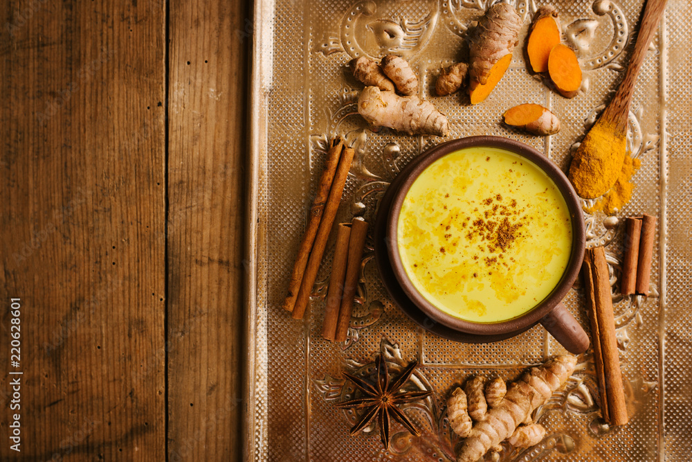 Hot turmeric milk with spices on wooden table Hot turmeric milk with spices on wooden table
