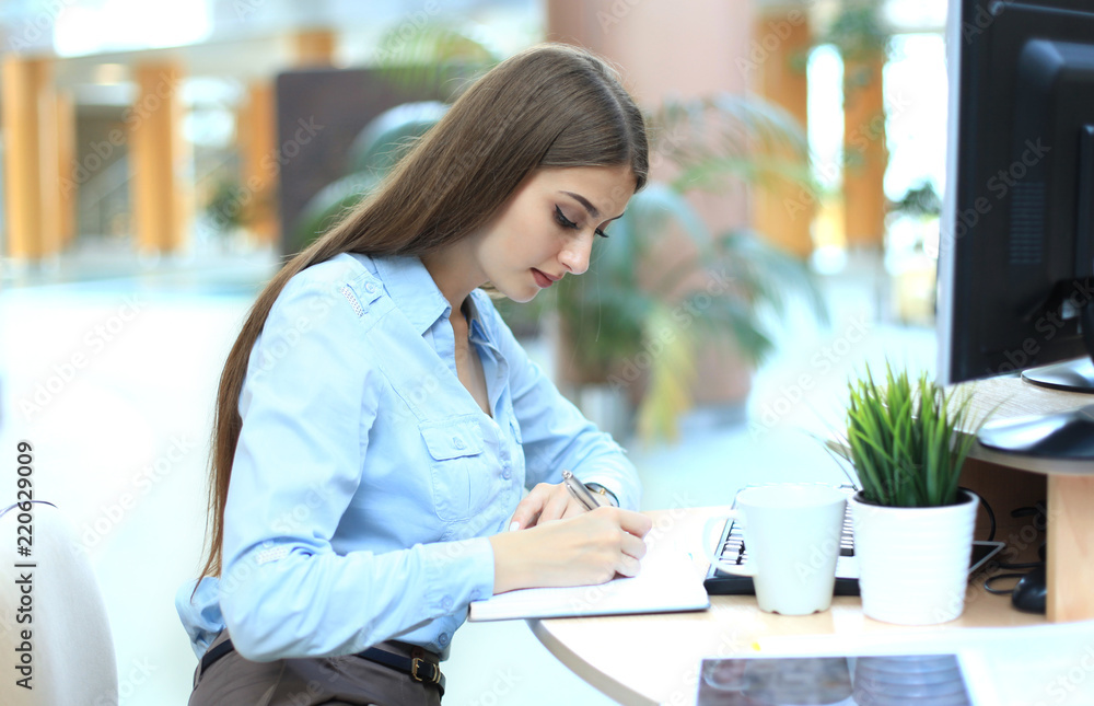 Young woman at workplace going through notes in diary. Young woman at workplace going through notes in diary.