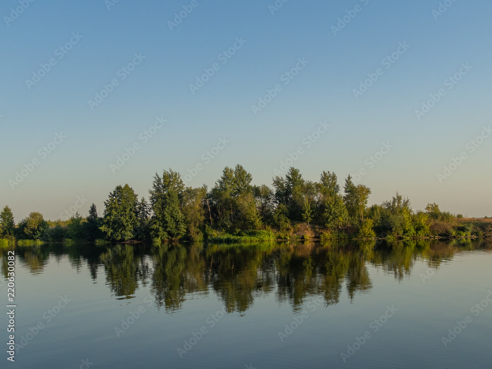 River landscape. Beautiful view of the full-flowing river from the high steep Bank, overgrown with grass. The blue surface of the water, cloudy sky and green grass on the opposite Bank of the river