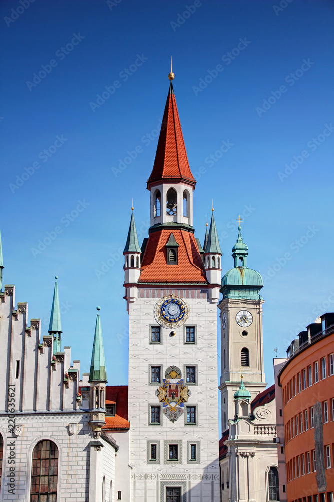 Obraz premium Ornate Gothic bell tower of former town hall Altes Rathaus in Marienplatz square in historic center of Munchen Altstadt district with tower of Heilig-Geist church in background, Bayern Germany Europe