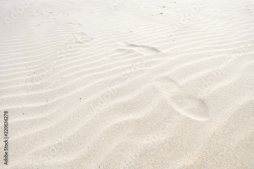 Footprints on the white sand waves beach background.