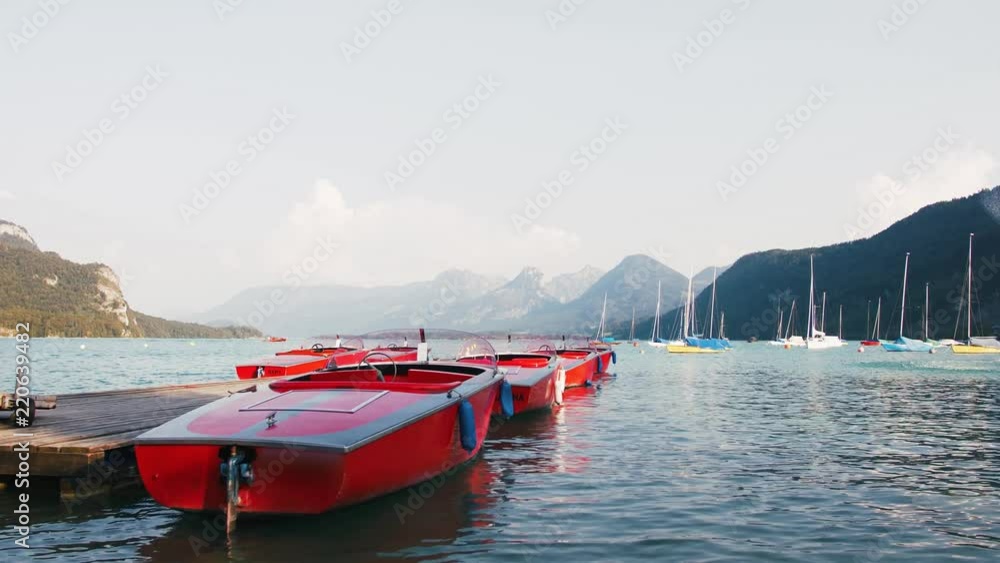 Colorful red boats on stunning mountain lake in Alps during sunset Colorful red boats on stunning mountain lake in Alps during sunset