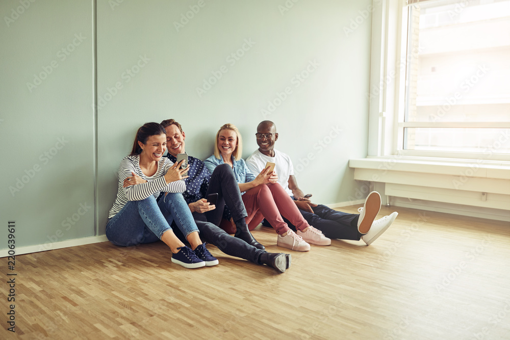 Young businesspeople sitting on an office floor taking a break Young businesspeople sitting on an office floor taking a break