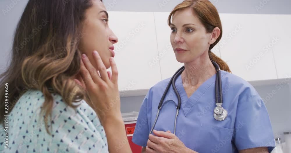 Senior nurse examines womans lymph nodes on neck to determine if swollen Senior nurse examines womans lymph nodes on neck to determine if swollen