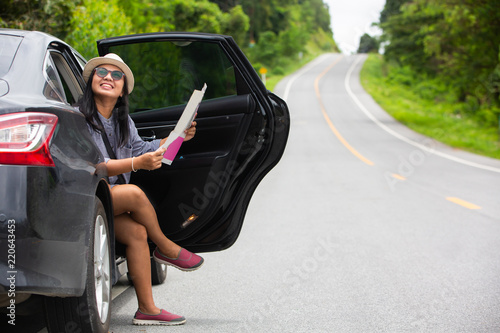 Asian traveler woman using mobilephone and map beside car at hill road . Travel concept