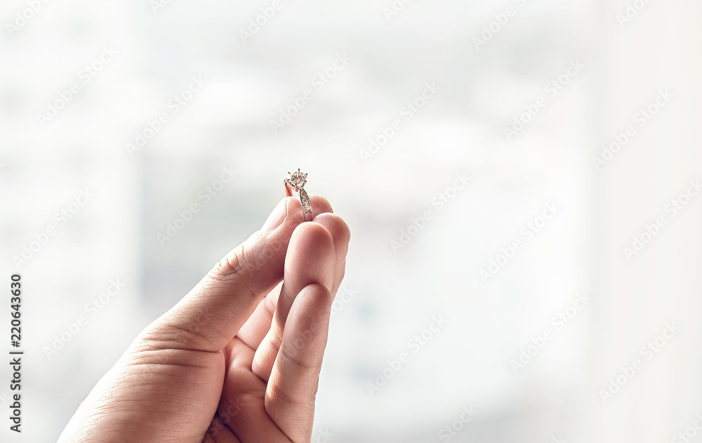 Obraz premium ็Hand hold diamond ring with blur background. symbol of wedding, marriage and love.