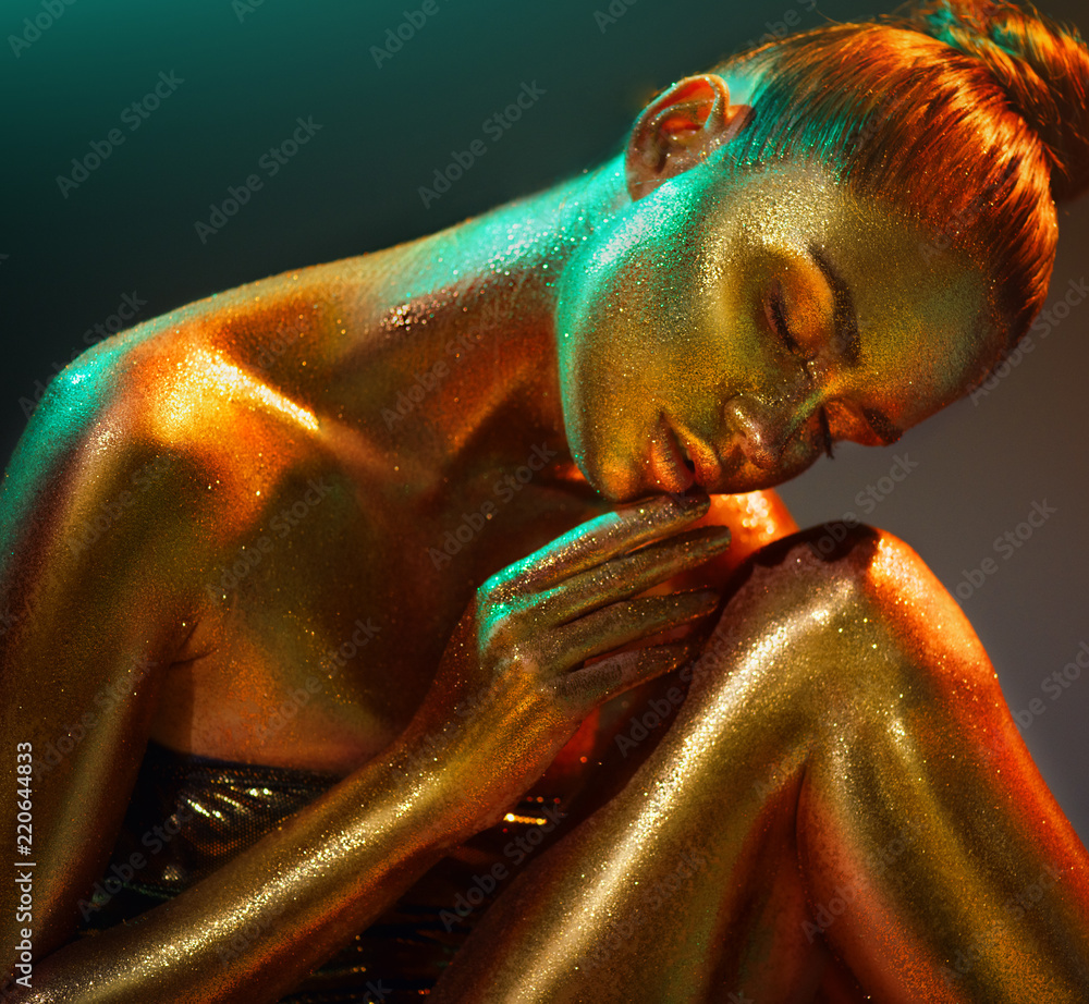 Fashion model girl in colorful bright golden sparkles on her body in neon lights posing, of beautiful girl with glowing makeup. Glitter vivid neon skin, body art Stock Photo | Adobe