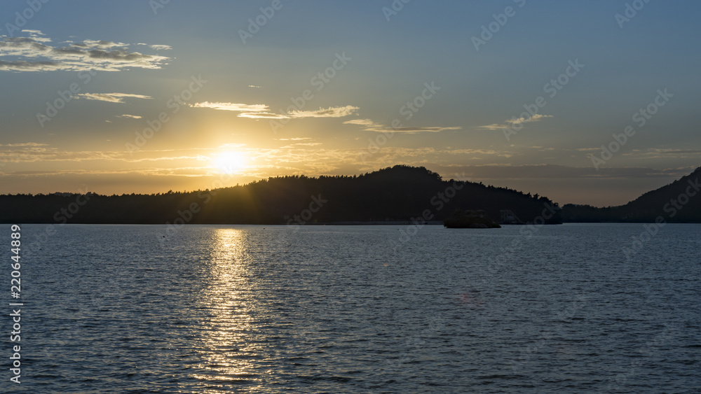 Sunset above the horizon and lake. Dusk above the lake. Evening nature by lake. Silhouette of horizon.