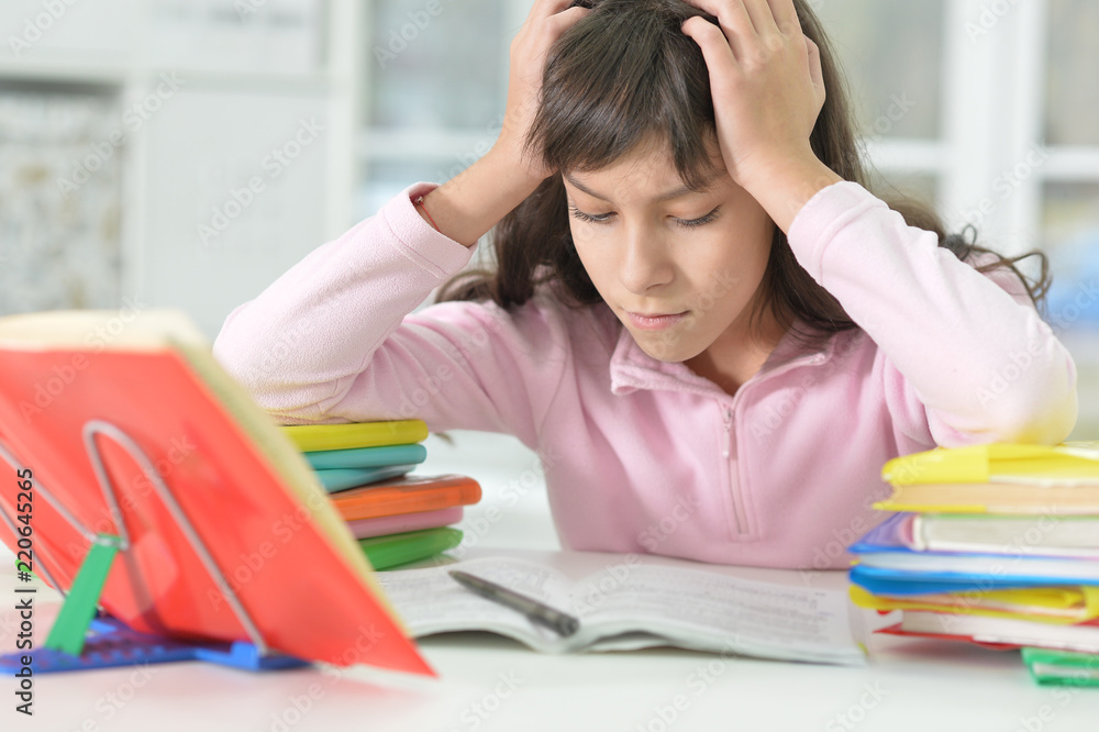Tired schoolgirl sitting at desk and studying Tired schoolgirl sitting at desk and studying