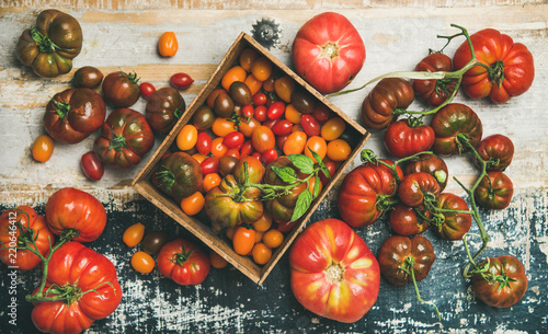 Flat-lay of fresh colorful ripe Fall or Summer heirloom, bunch and cherry tomatoes over rustic wooden background, top view, horizontal composition. Local market seasonal produce