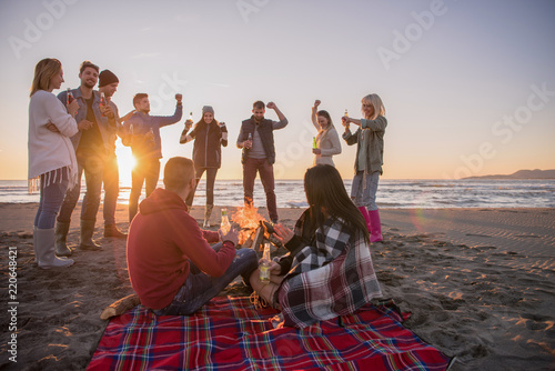 Couple enjoying with friends at sunset on the beach photo