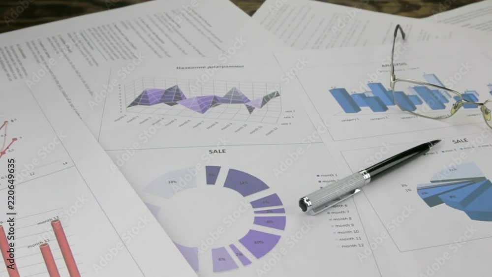 Office desk with business report, glasses, pen and mobile phone. Slider shot.