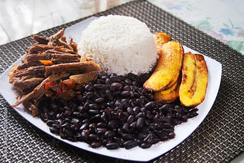 Homemade Venezuelan food. Traditional Venezuelan dish. Pabellon Criollo. White Rice, Black beans,Fried plantains, and Shredded beef photo