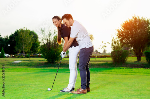 Male instructor showing woman to play golf