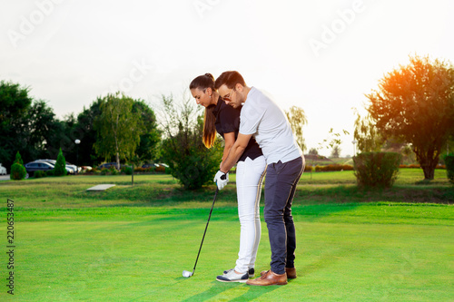 Male instructor showing woman to play golf