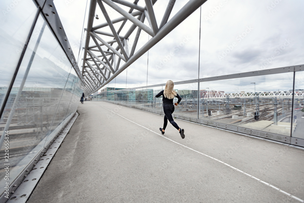 Sporty young woman running fast in city environment