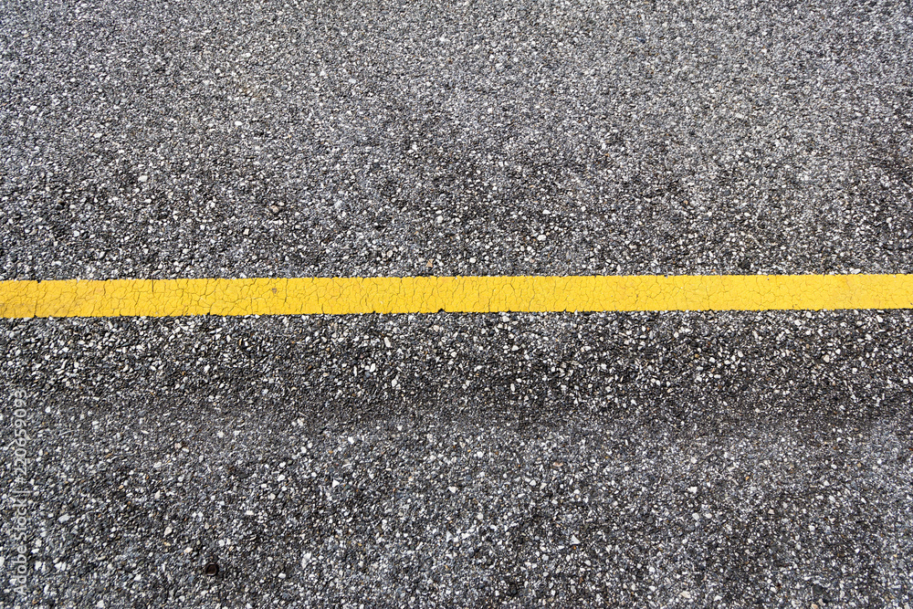 Fototapeta premium Top view of a tarmac road surface with yellow horizontal traffic line as background
