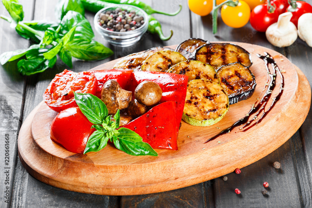 Grilled vegetables, mushrooms, tomatoes, eggplant, pepper on cutting board on wooden background. Healthy food. Top view Grilled vegetables, mushrooms, tomatoes, eggplant, pepper on cutting board on wooden background. Healthy food. Top view