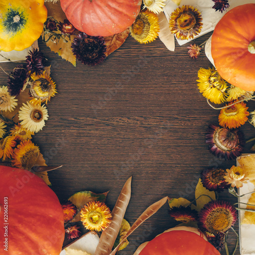 Thanksgiving background with autumn dried flowers, pumpkins and fall leaves on the old wooden background. Abundant harvest concept