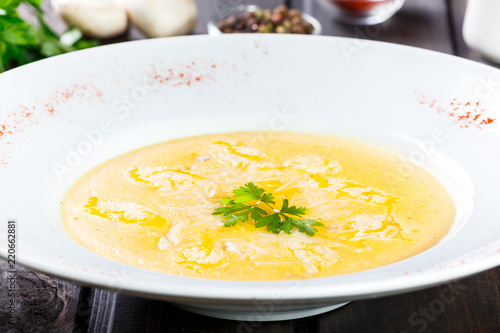 Cream soup with cheese parmesan, herbs and chicken on plate on dark wooden background. Homemade food. Ingredients on table