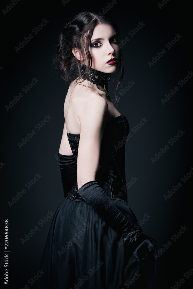 Dramatic portrait of beautiful sad gothic girl among dark