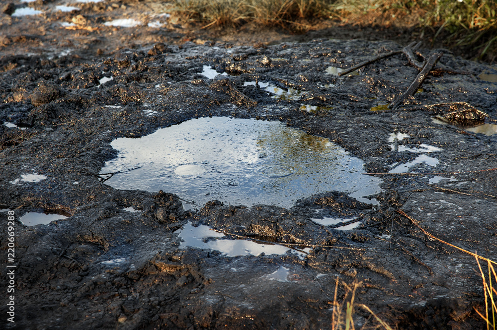 Fototapeta premium Spills of crude oil on the soil surface. Crater of the volcano.Mud volcano