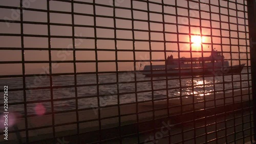 Ship in background at sunset seen through fence slow motion