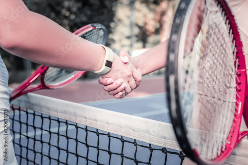 Respect partner. Close up of female young hands shaking and carrying rackets © zinkevych