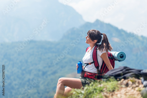 Active female tourist with backpack holding bottle of water
