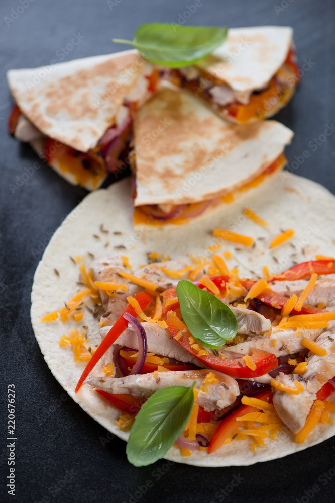 Quesadilla or tortilla wheat wrap with grilled chicken meat, vegetables and cheddar, studio shot Quesadilla or tortilla wheat wrap with grilled chicken meat, vegetables and cheddar, studio shot