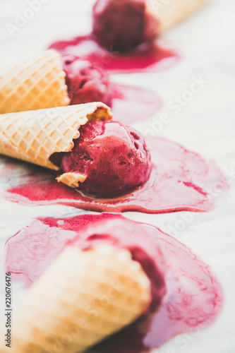 Fresh summer dessert. Melting natural raspberry sorbet ice-cream scoops in sweet waffle cones over marble background, selective focus. Healthy vegan sweet food