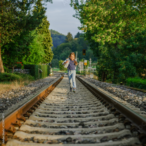 Cute little schoolgirl walking along tha railway