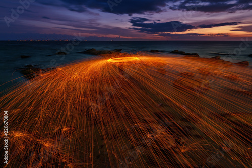 Fire spining at the sea with sunset sky