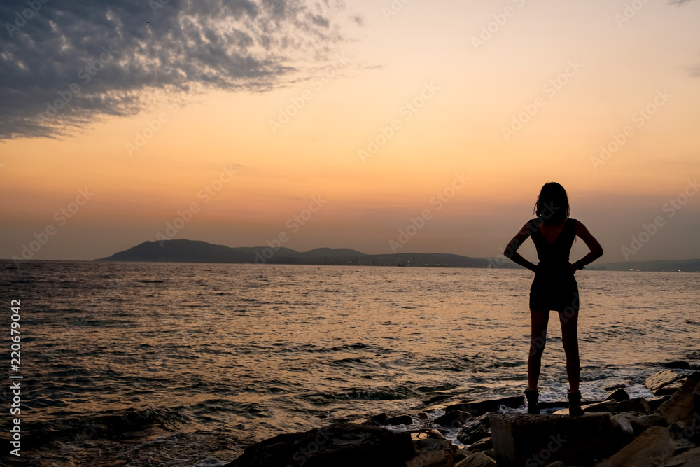 Silhouette of a girl at sunset near the sea