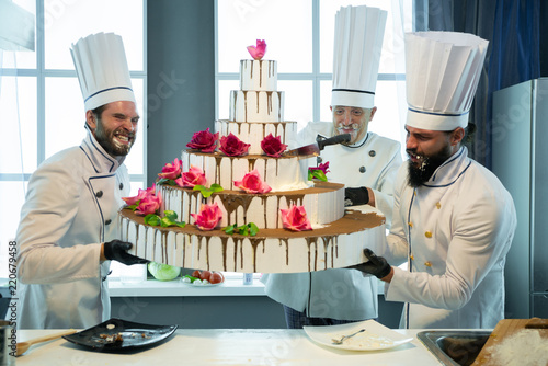Canvas-taulu Three cooks are holding a huge cake
