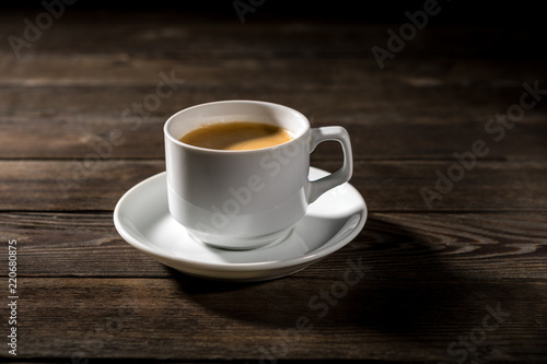 Black coffee in white cup on black wood background