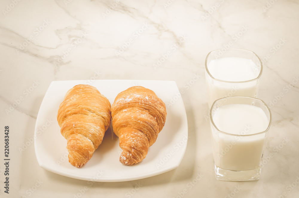 breakfast with croissants and milk/croissants in a white plate and two glasses milk on a white background. Selective focus breakfast with croissants and milk/croissants in a white plate and two glasses milk on a white background. Selective focus