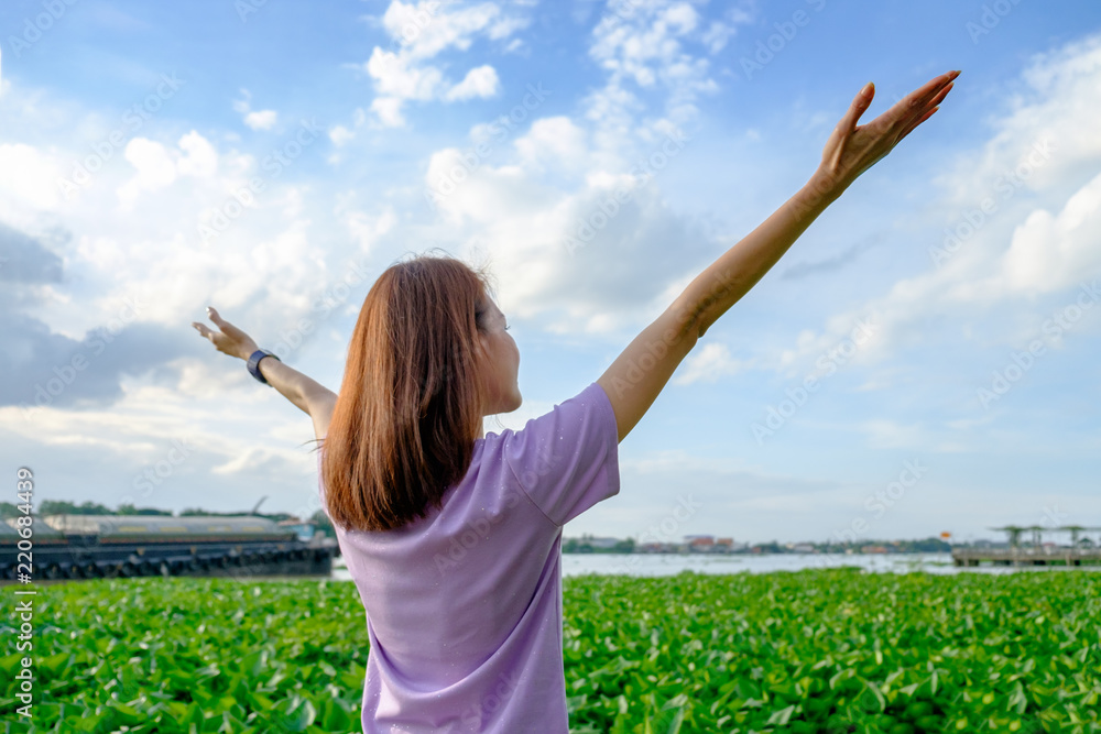 Happy woman tourist standing and raise her hands up on green water plant with blue sky at side of river. Happy woman tourist standing and raise her hands up on green water plant with blue sky at side of river.