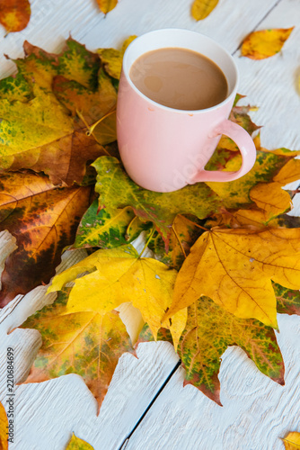 Coffee cup and yellow autumn leaves background. Still life, top of view, flat lay.