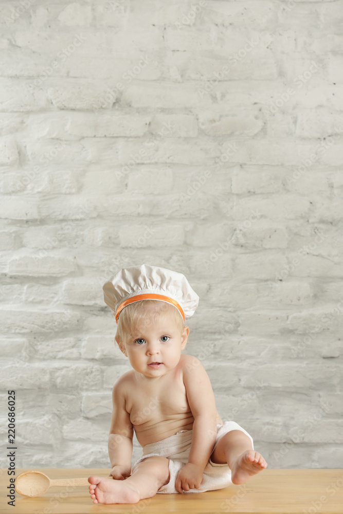 Baby chef - indoor portrait of an adorable baby with chef hat and wooden spoon Baby chef - indoor portrait of an adorable baby with chef hat and wooden spoon