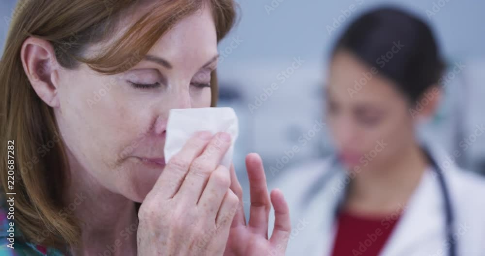 Attractive mid aaged patient blowing nose into tissue paper Attractive mid aaged patient blowing nose into tissue paper