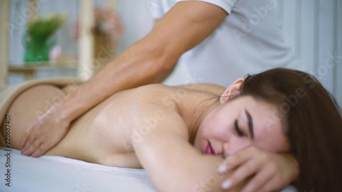 Male masseur hands massaging beautiful woman back in spa salon. Young female enjoying professional spine and back treatment. Rehabilitation, medicine, manual therapy, beauty, health and skin concept