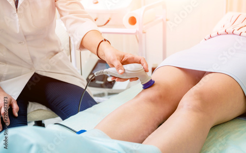 Fotografie Doctor using machine to treat the knee joints of a patient